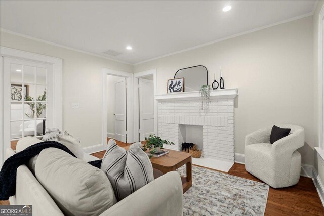 living room with ornamental molding, hardwood / wood-style floors, and a brick fireplace