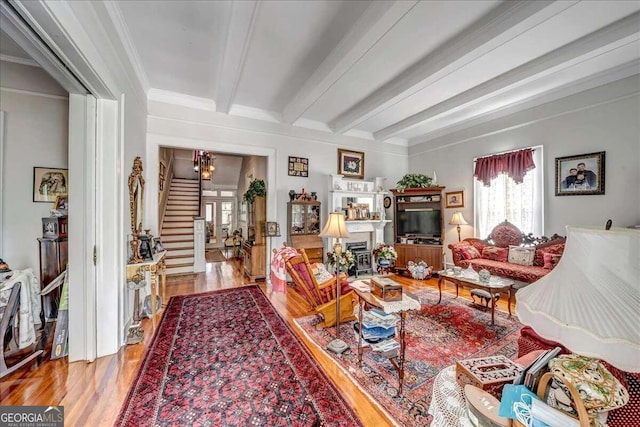 living room featuring crown molding, a notable chandelier, beamed ceiling, and light hardwood / wood-style flooring