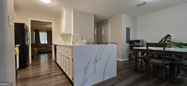 kitchen featuring sink, white cabinetry, black fridge, a textured ceiling, and dark hardwood / wood-style flooring