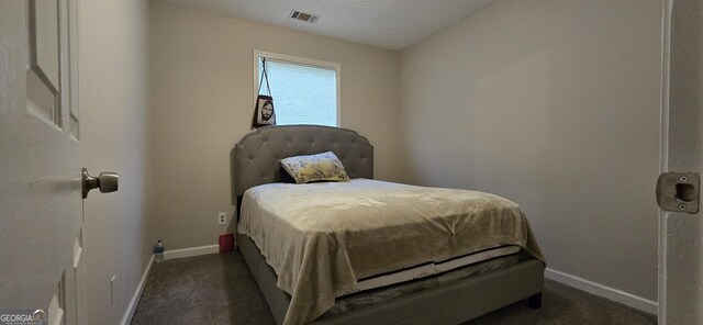 bedroom featuring dark carpet and a textured ceiling