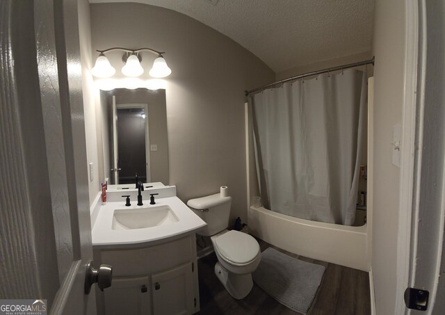 full bathroom with wood-type flooring, shower / bath combination with curtain, vanity, toilet, and a textured ceiling