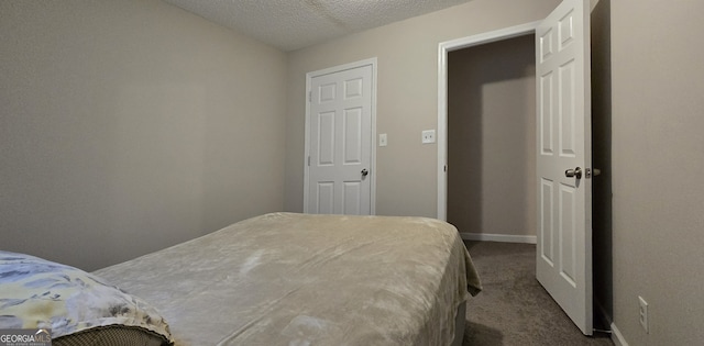 bedroom featuring dark carpet and a textured ceiling