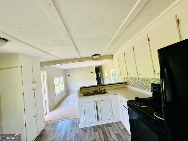 kitchen featuring kitchen peninsula, black appliances, light colored carpet, decorative backsplash, and sink