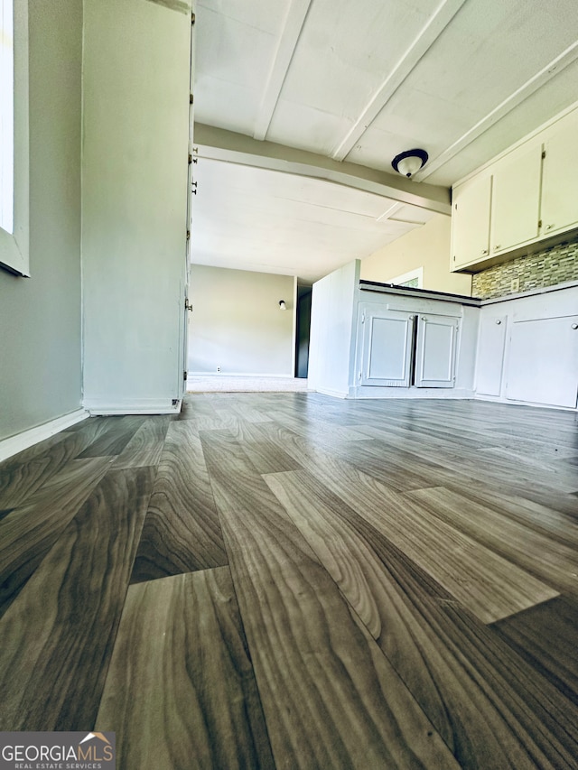 interior space featuring beamed ceiling, white cabinetry, and hardwood / wood-style flooring