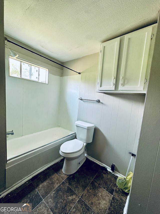 bathroom with tub / shower combination, tile patterned flooring, toilet, and a textured ceiling