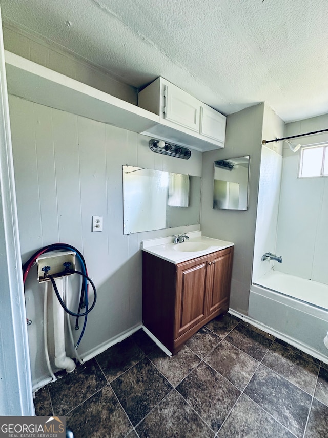 interior space with tile patterned floors, bathtub / shower combination, vanity, and a textured ceiling