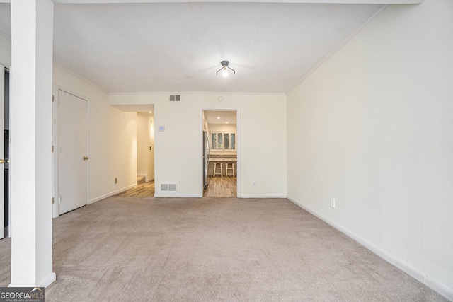 spare room with crown molding and light colored carpet