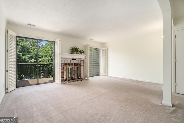 unfurnished living room featuring a tile fireplace, light carpet, and a textured ceiling