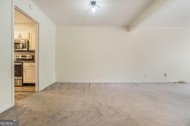 empty room with beamed ceiling, ornamental molding, and light carpet