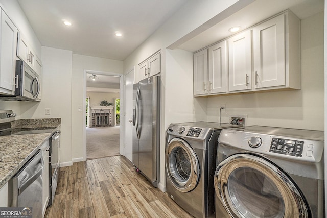 clothes washing area featuring washer and dryer and light hardwood / wood-style floors