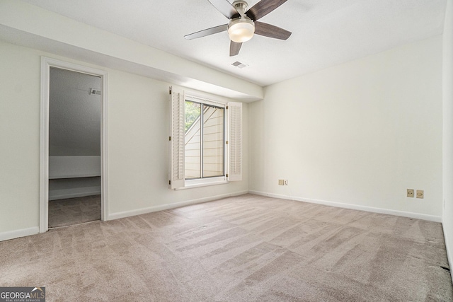 unfurnished bedroom with light carpet, a spacious closet, and ceiling fan