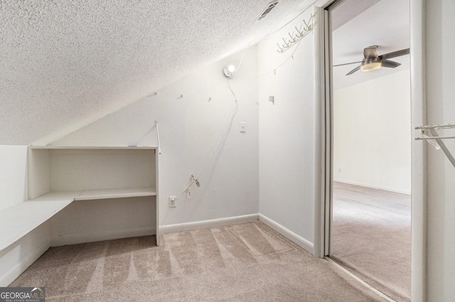 interior space featuring light carpet, ceiling fan, vaulted ceiling, and a textured ceiling