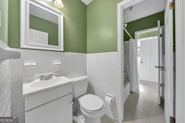 full bathroom featuring tile walls, toilet, shower / bath combo, vanity, and a textured ceiling