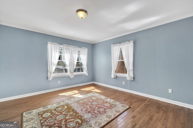 spare room with ornamental molding, hardwood / wood-style flooring, and baseboards