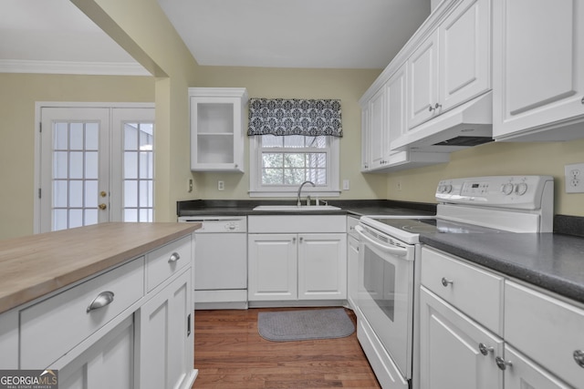 kitchen with dark countertops, white appliances, white cabinets, and a sink