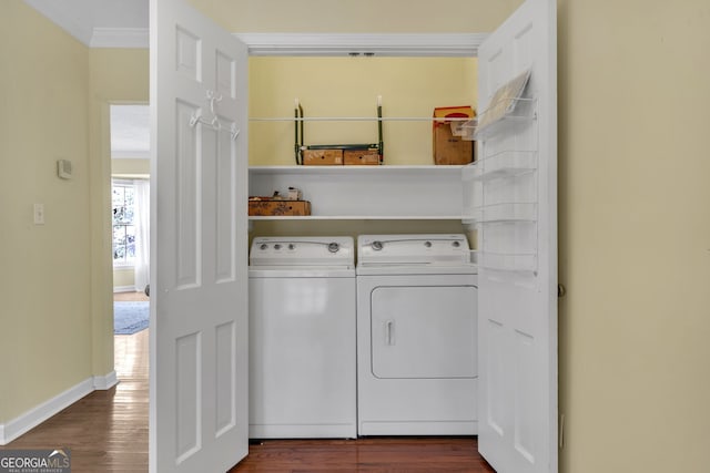 clothes washing area featuring dark wood-type flooring, ornamental molding, laundry area, independent washer and dryer, and baseboards