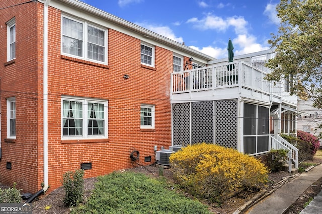 view of home's exterior with a sunroom, crawl space, brick siding, and central air condition unit