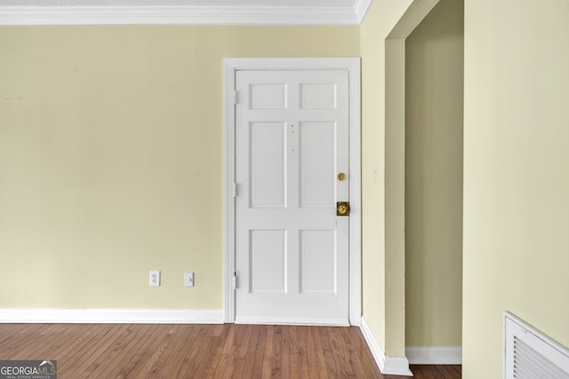 interior space featuring ornamental molding, wood finished floors, visible vents, and baseboards