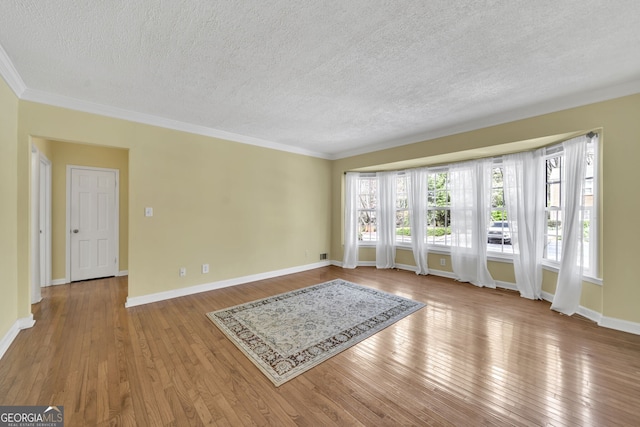 unfurnished living room featuring a textured ceiling, ornamental molding, light wood-style flooring, and baseboards