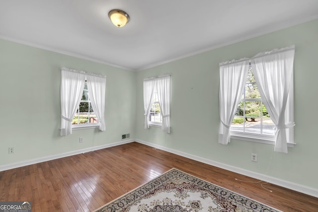 empty room featuring ornamental molding, baseboards, and hardwood / wood-style flooring