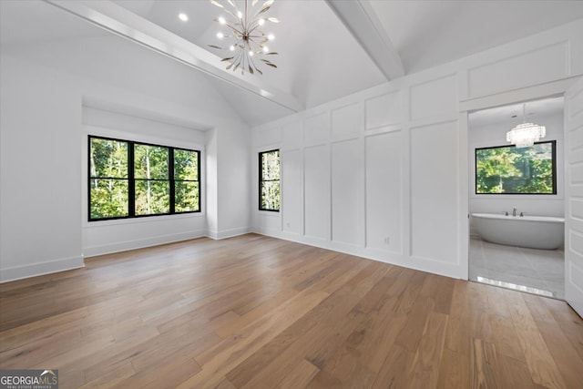 unfurnished bedroom with lofted ceiling with beams, hardwood / wood-style flooring, ensuite bath, and a chandelier