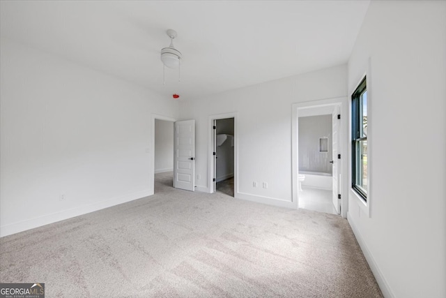 unfurnished bedroom with a spacious closet, ceiling fan, a closet, connected bathroom, and light colored carpet