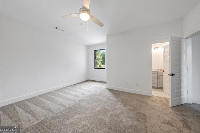 unfurnished bedroom featuring ceiling fan, light colored carpet, and connected bathroom