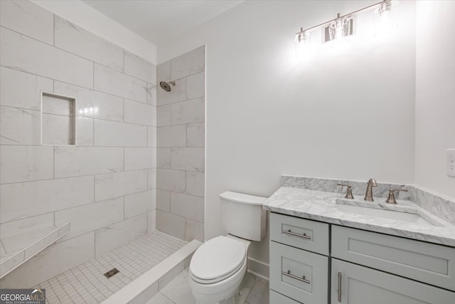 bathroom featuring vanity, toilet, and tiled shower