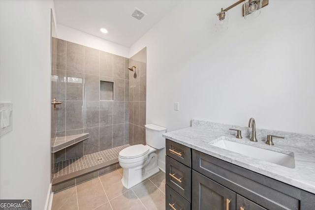 bathroom featuring tile patterned flooring, vanity, tiled shower, and toilet