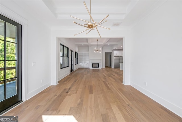 unfurnished living room with a notable chandelier, light hardwood / wood-style flooring, and a tray ceiling