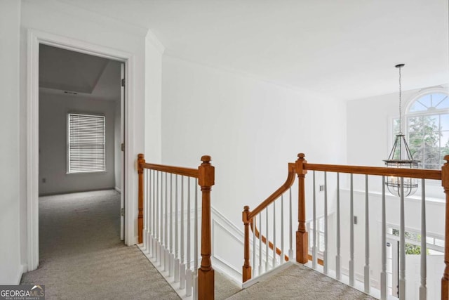 hallway featuring plenty of natural light, carpet flooring, and a notable chandelier