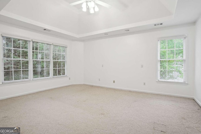 carpeted spare room with a raised ceiling, vaulted ceiling, and ceiling fan