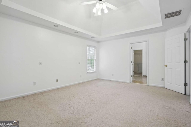 carpeted empty room with a raised ceiling and ceiling fan