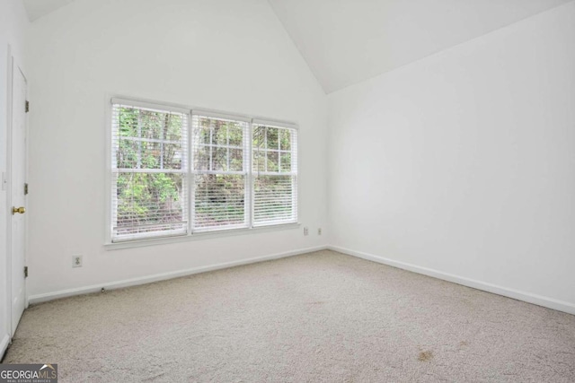 empty room with carpet floors and high vaulted ceiling