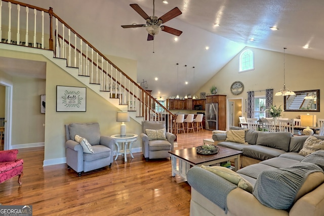 living room with hardwood / wood-style flooring, high vaulted ceiling, and ceiling fan