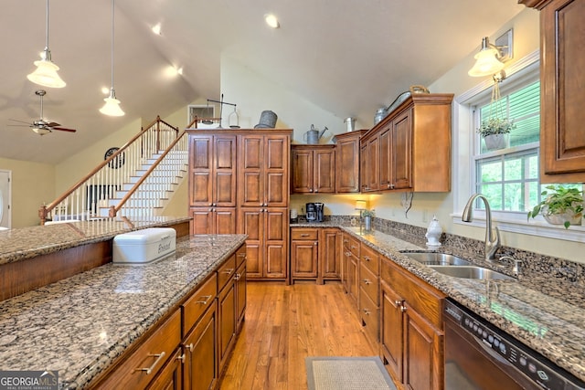 kitchen with decorative light fixtures, black dishwasher, sink, dark stone counters, and light wood-type flooring