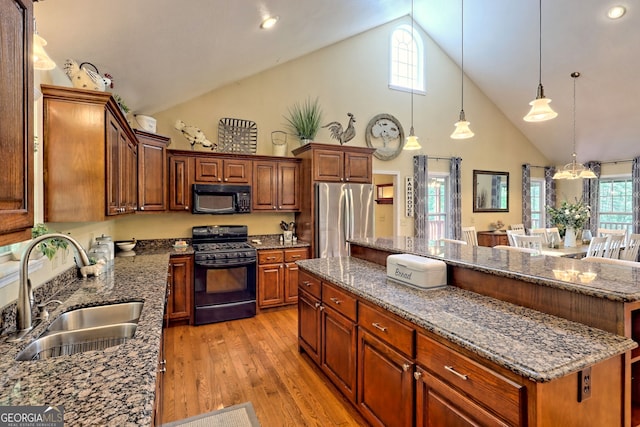 kitchen featuring black appliances, high vaulted ceiling, light wood-type flooring, sink, and a center island