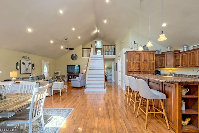 dining room featuring ceiling fan, high vaulted ceiling, and light hardwood / wood-style floors