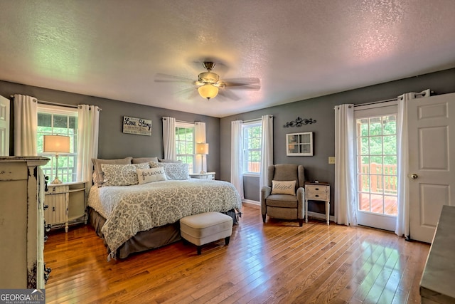 bedroom featuring wood-type flooring, a textured ceiling, and access to outside