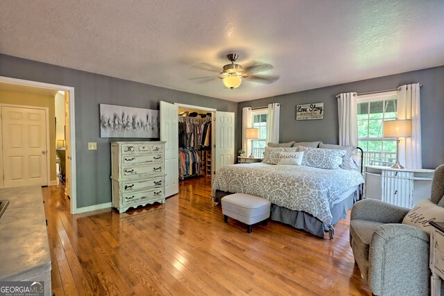 bedroom featuring ceiling fan, a closet, hardwood / wood-style floors, and a spacious closet