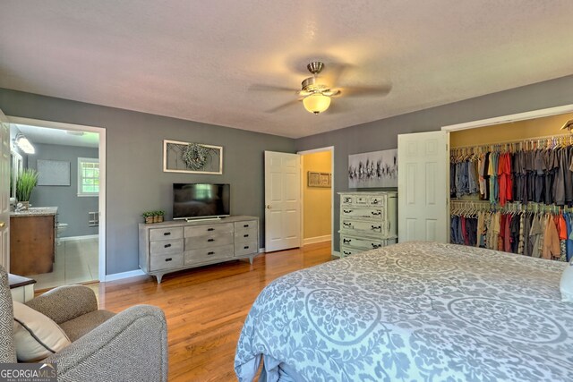 bedroom with wood-type flooring, connected bathroom, a closet, and ceiling fan