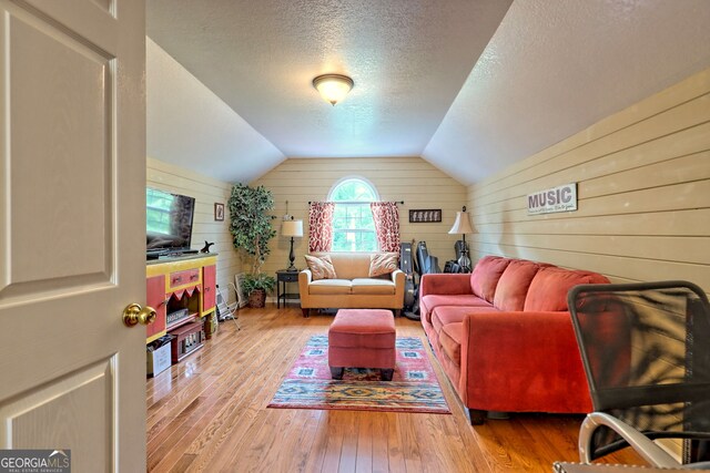 living room featuring wooden walls, lofted ceiling, and light wood-type flooring