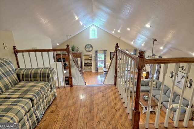 interior space featuring light hardwood / wood-style floors, lofted ceiling, ceiling fan, and a textured ceiling