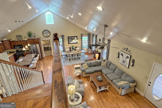 living room with ceiling fan, high vaulted ceiling, a wealth of natural light, and light hardwood / wood-style floors