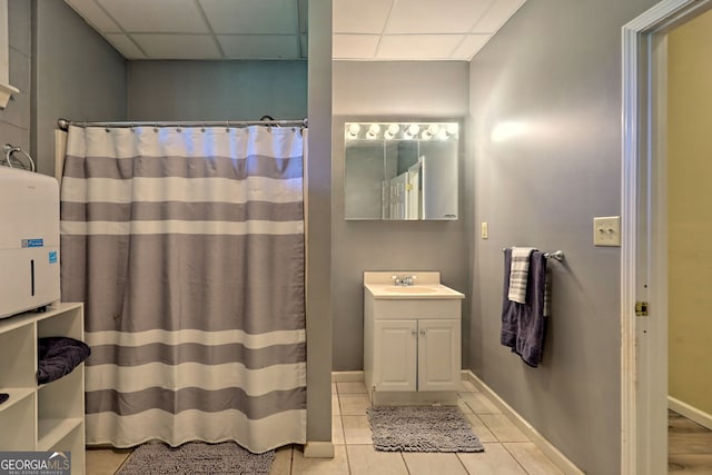 bathroom with tile patterned flooring, vanity, and a paneled ceiling