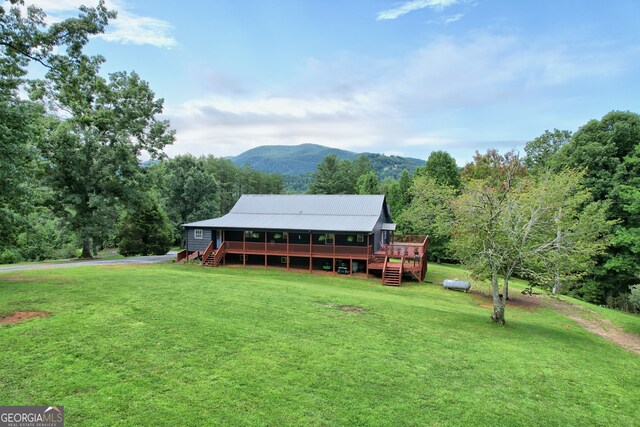 rear view of property with a deck with mountain view and a yard