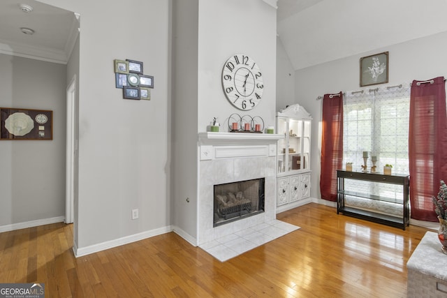 140 Wisteria Blvd, Covington, GA 30016 - living room with crown molding, baseboards, lofted ceiling, a tile fireplace, and hardwood / wood-style flooring