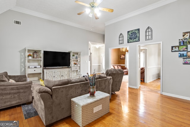 living room with a high ceiling, ornamental molding, ceiling fan, and light hardwood / wood-style floors