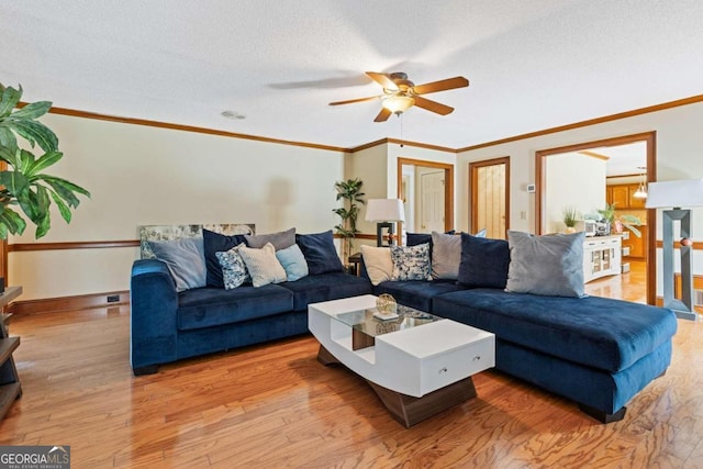 living room with ceiling fan, crown molding, light wood-type flooring, and a textured ceiling