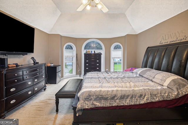 bedroom featuring a tray ceiling, ceiling fan, stainless steel fridge, and light colored carpet